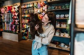 Pet shop owners stands in her shop with a black poodle in her arms