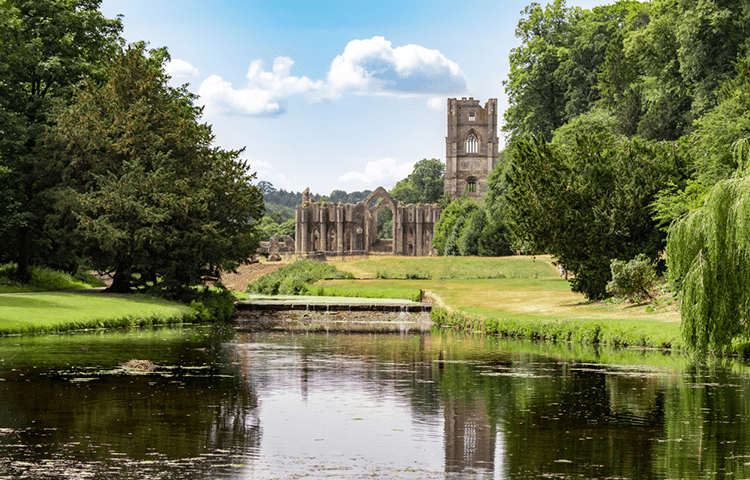 Landscape view of Fountains Abbey and Studley Royal across the lake, the perfect park for professional dog walkers in the UK